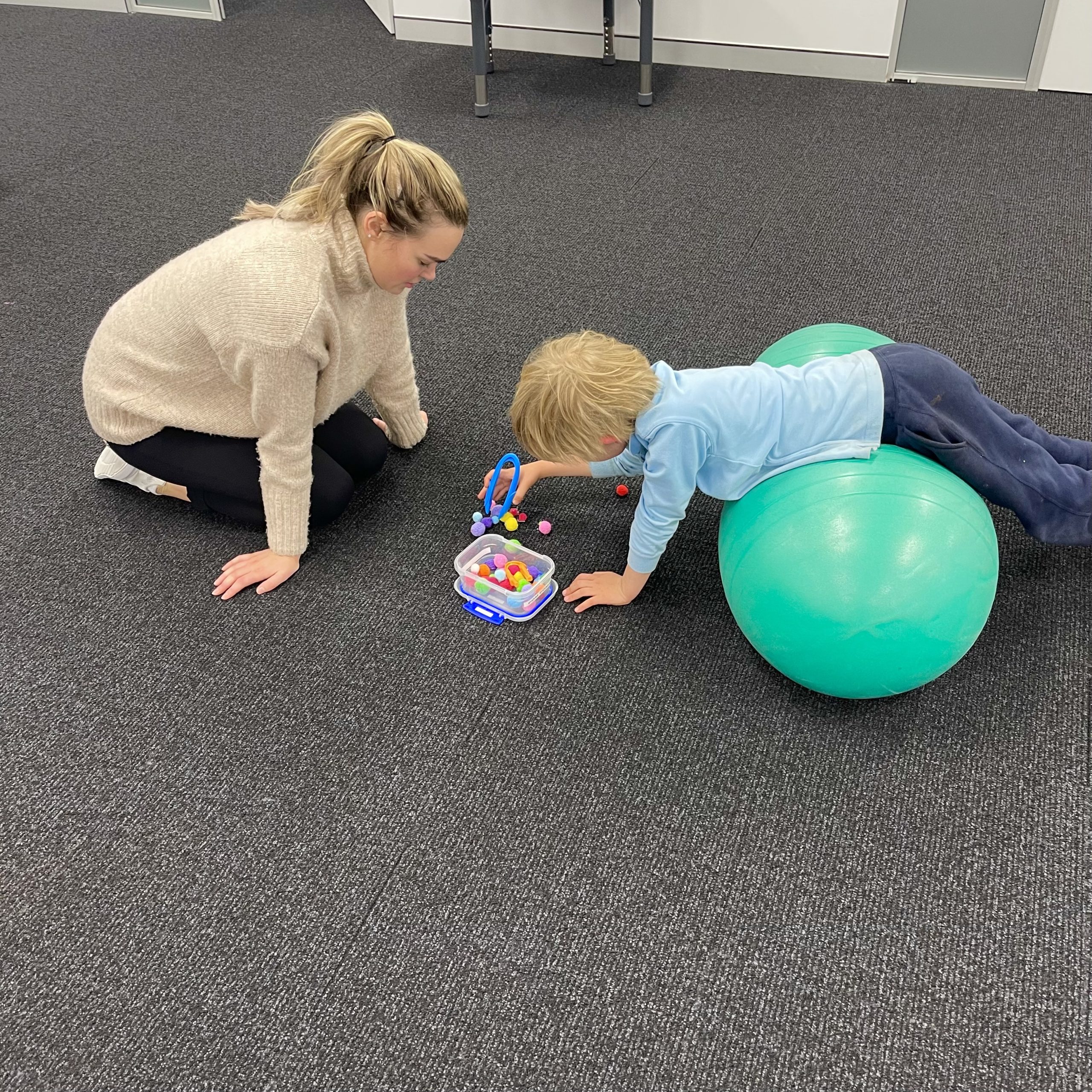 Boy doing tummy time on gym ball to help attention and regulation with Occupational Therapist in occupational therapy gym in Bondi Junction an dMascot